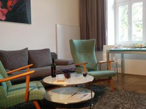 uma sala de estar com um sofá, cadeiras e uma mesa em Apartments Maximillian em Viena