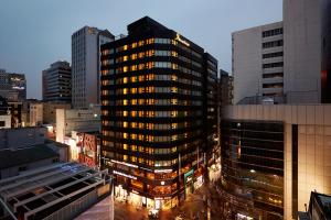 um edifício alto numa cidade à noite em Nine Tree Hotel Myeongdong em Seul