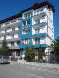 un edificio azul y blanco con un coche aparcado delante de él en Pensiunea Maria Costinesti, en Costinesti