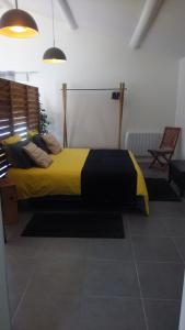 Un dormitorio con una cama con una manta amarilla y negra. en Gîte La Malonière, en Saint-Martin-du-Bois