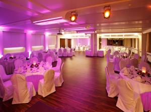 a banquet hall with white tables and chairs and purple lighting at Hotel Schönbuch in Pliezhausen