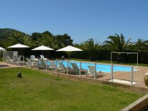 - une rangée de chaises et de parasols à côté de la piscine dans l'établissement Residence les Bell'ombres, à Cargèse