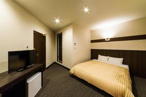a hotel room with a bed and a flat screen tv at Hotel CASVI Tenjin in Fukuoka