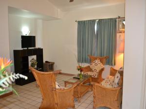 a living room with chairs and a table and a television at West Plaza Malakal in Koror