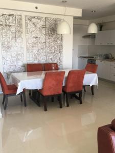 a dining room with a white table and red chairs at Shave Tsion Apartment in the center Ashdod in Ashdod