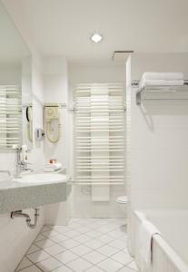 a white bathroom with a sink and a shower at Centro Hotel National Frankfurt City in Frankfurt