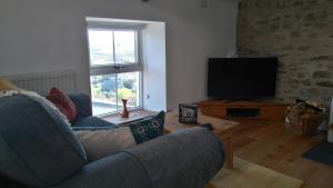 a living room with a couch and a television at Brynawel in Saint Dogmaels