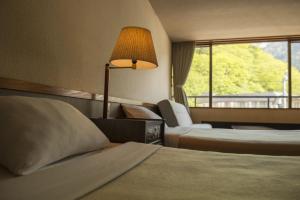 um quarto de hotel com duas camas e um candeeiro em Nakamurakan em Takayama