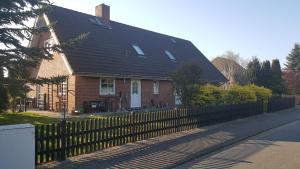 a brown house with a black roof and a fence at Ferienwohnungen An der Ostsee in Wittenbeck