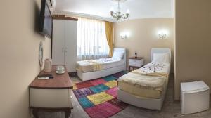 a bedroom with two beds and a table and a television at Ozmen Hotel in Antalya