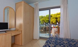 a bedroom with a bed and a tv and a window at Hotel Antares in Alba Adriatica