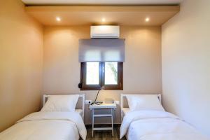 two beds in a room with a table and a window at Kissos Apartments in Vourvourou