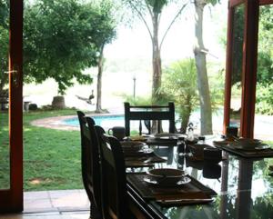 a wooden table with chairs and a table with plates and dishes at River Bank Lapa in Upington