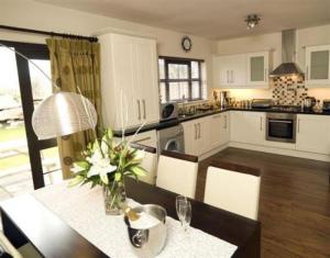 a kitchen with a table with a vase of flowers on it at Kenmare Bay Hotel Lodges in Kenmare