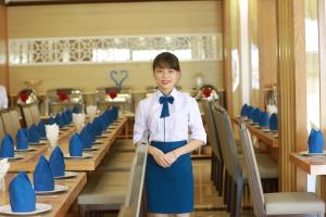 a woman wearing a tie standing in a dining room at Blue Wave Hotel in Cửa Lô