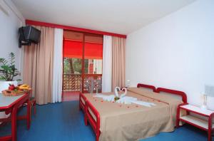 una camera con due letti, un tavolo e una finestra di Hotel Marina 2 a Marina di Campo