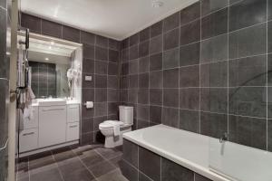 a bathroom with a tub and a toilet and a sink at Pure Chalet Thredbo in Thredbo