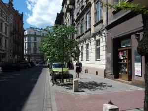 a person walking down a street with a green car at Lemon Tree Hostel in Kraków