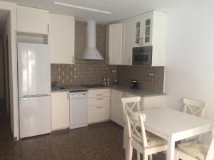 eine weiße Küche mit einem Tisch und einem weißen Kühlschrank in der Unterkunft Apartamento Abadia Teruel in Teruel