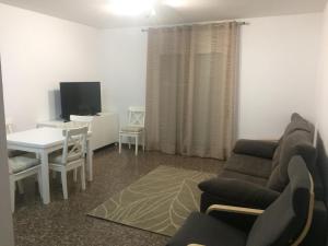 ein Wohnzimmer mit einem Sofa, einem Tisch und einem TV in der Unterkunft Apartamento Abadia Teruel in Teruel