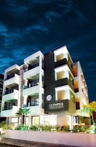un edificio blanco y negro con palmeras delante en Olympus Thalassea Hotel, en Paralia Katerinis