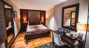 1 dormitorio con cama, escritorio y espejo en The Torrance Hotel, en East Kilbride