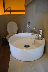 a white sink in a bathroom with a toilet at Jachthaven Nieuwboer in Bunschoten