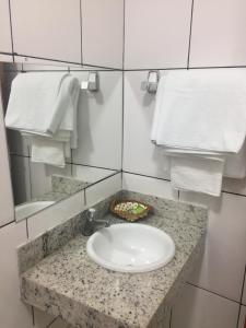 a bathroom counter with a white sink and towels at Hotel Caroline in Timon +50 photos