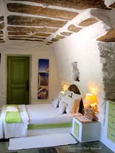 um quarto com uma cama branca e uma porta verde em La Maison Vert Amande em Spathi 