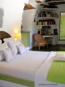 a bedroom with a large white bed and a chair at La Maison Vert Amande in Spathi 