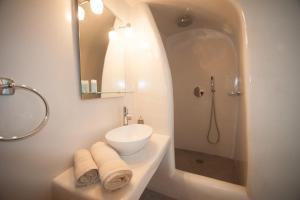 a white bathroom with a sink and a shower at Lefteris Traditional Rooms in Fira
