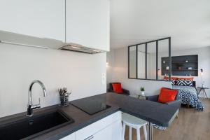 a kitchen with a sink and a living room at Stay Appart Hotel Lille Centre in Lille