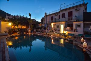 una piscina con sillas y edificios por la noche en Charme Hotel La Villa Tina, en Isquia
