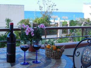 a table with two glasses of wine and a basket of fruit at Stella Marina Sea & Sun in Cefalù