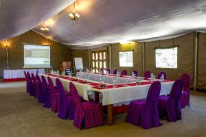 une grande table avec des chaises violettes dans une tente dans l'établissement Ngorongoro Serena Safari Lodge, à Ngorongoro