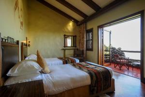 a bedroom with two beds and a large sliding glass door at Ngorongoro Serena Safari Lodge in Ngorongoro +17 photos