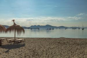 a beach with a chair and an umbrella and the water at Apartamentos Massol in Port de Pollensa +7 photos