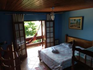 a bedroom with a bed and a sliding glass door at Pousada Tony Montana in Praia de Araçatiba