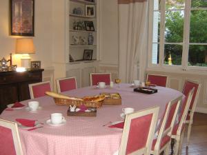 einen Esstisch mit einem rosa Tischtuch und Stühlen in der Unterkunft Le clos saint Genois in Saint-Genis-Laval