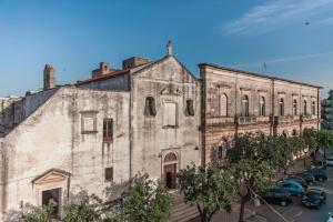 un vecchio edificio con auto parcheggiate in un parcheggio di Monolocale finemente ristrutturato a Ostuni