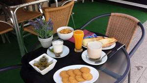 uma mesa com comida, bebidas e biscoitos em Albergue Ultreia em Arzúa