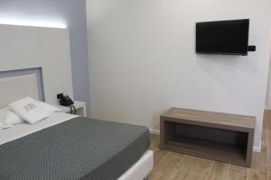 a bedroom with a bed and a tv on the wall at La Porta del Sole Hotel & Village in San Ferdinando