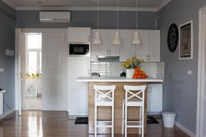 a kitchen with white cabinets and a counter with stools at Apartments O la la in Zagreb