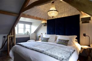 a bedroom with a large bed with a blue headboard at Walnut Cottage in Moreton in Marsh