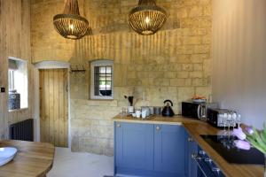 a kitchen with blue cabinets and a stone wall at Walnut Cottage in Moreton in Marsh