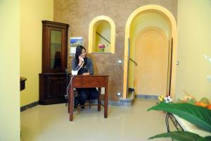 a woman sitting at a desk talking on a cell phone at Appartamenti Greso in Custonaci