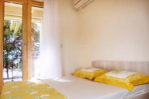 - une chambre avec un lit doté de draps jaunes et une fenêtre dans l'établissement Vasiliki Seaside Apartments, à Petrovac na Moru