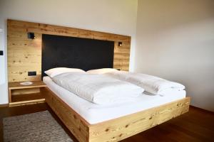 a bedroom with a large bed with a wooden headboard at Putzerhof in Funes