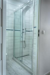 a shower with a glass door in a bathroom at Apartament Sto Metrów Od Morza in Świnoujście
