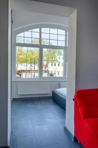 a bedroom with a red couch and a window at Apartament Sto Metrów Od Morza in Świnoujście